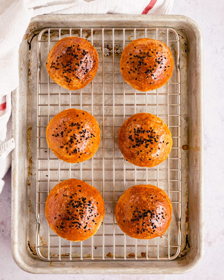 overhead shot of six burger buns on a baking tray