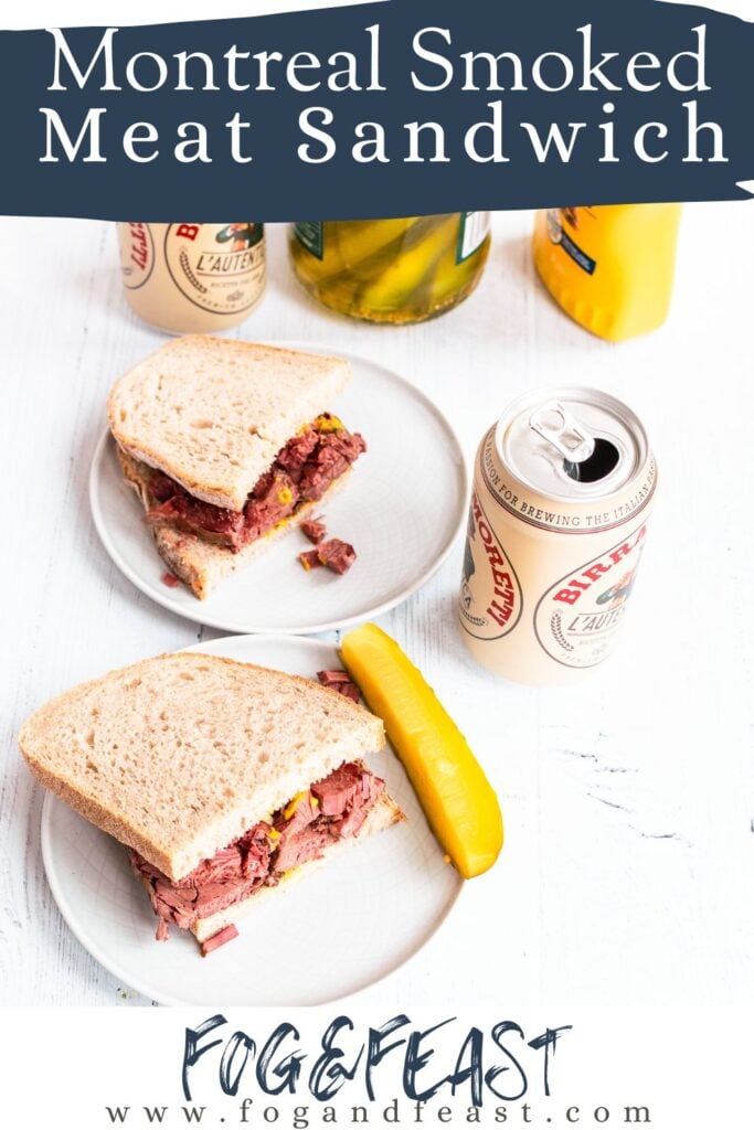 smoked meat sandwich on rye bread and mustard, a dill pickle on the side. Behind is a second half of a sandwich and two cans of beer.