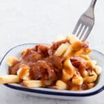 smoked meat poutine iin a dish with fork