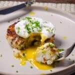 Golden Nova Scotia fish cakes with smoked haddock served with a poached egg on a cream plate.